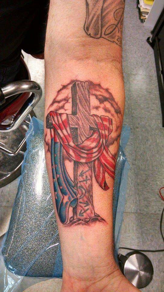 a person with a tattoo on their arm holding a cross and an american flag ribbon