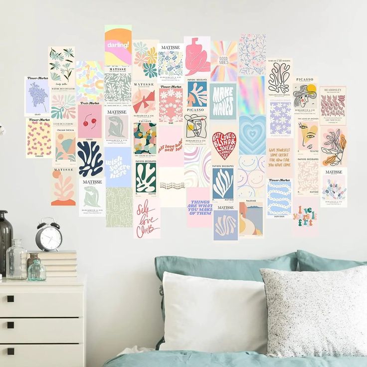 a bed sitting under a wall covered in lots of different types of posters on it