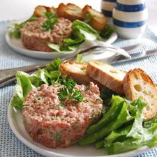 two plates filled with meat and lettuce on top of a blue table cloth