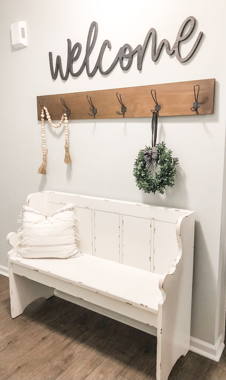 a white bench sitting in front of a welcome sign and wreath on top of it