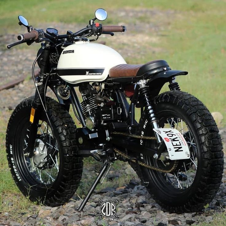 a white motorcycle parked on top of a rocky field