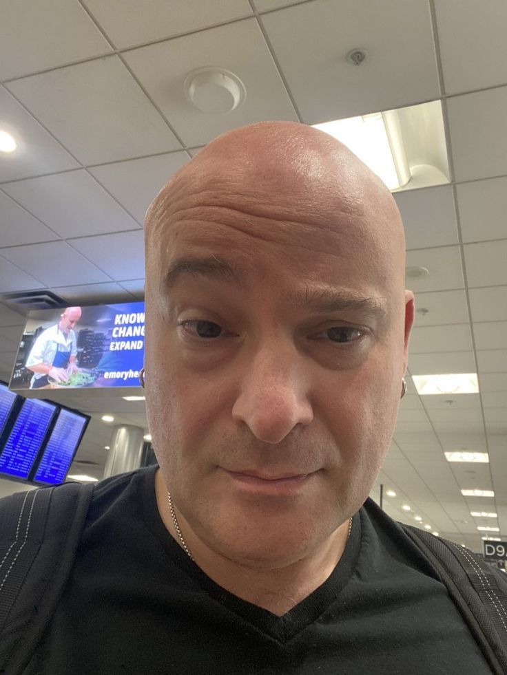 a bald man in an airport looking at the camera