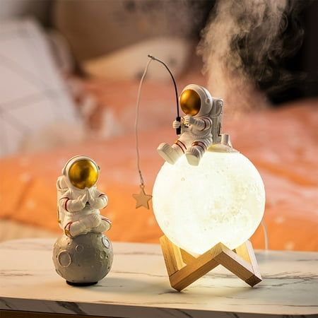 two small figurines sitting on top of a wooden table next to a lamp