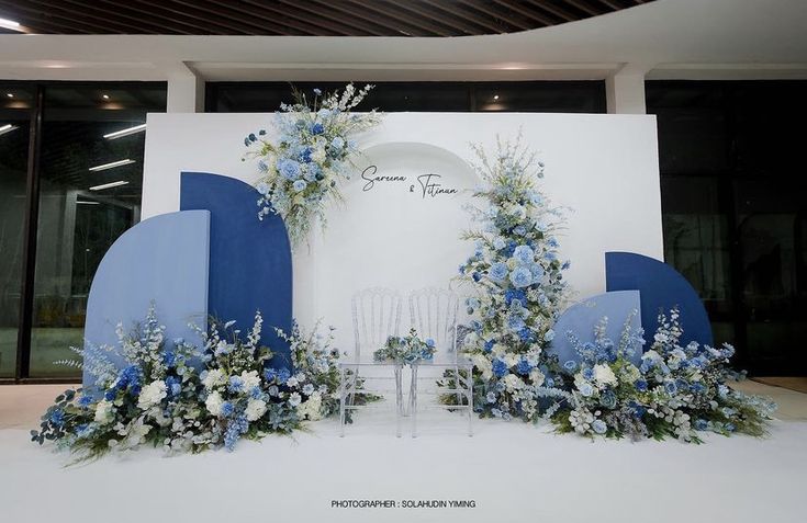 a blue and white wedding set up with flowers