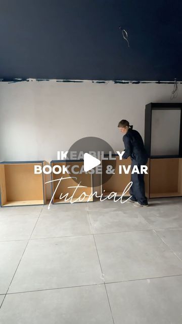 a man standing in front of a bookcase and tv on top of a tiled floor