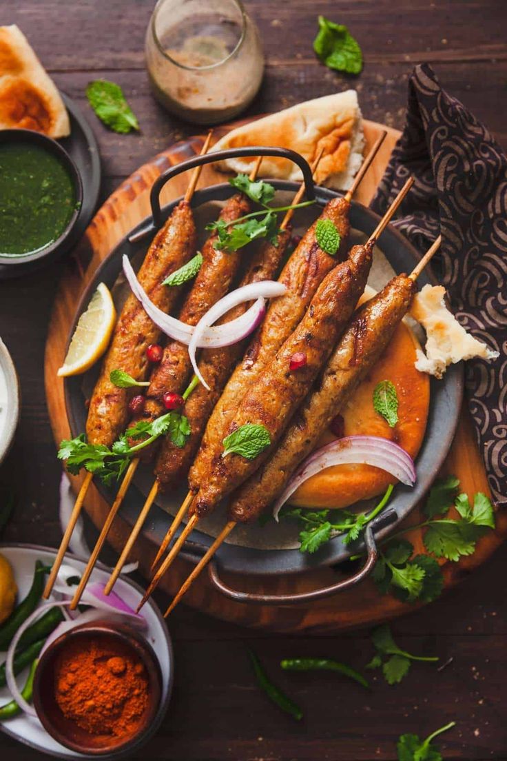 several skewers of food on a plate with dipping sauces