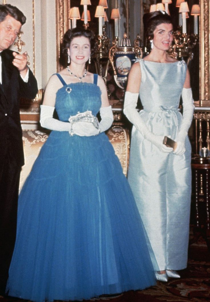 two women and a man in formal wear standing next to each other wearing evening gowns