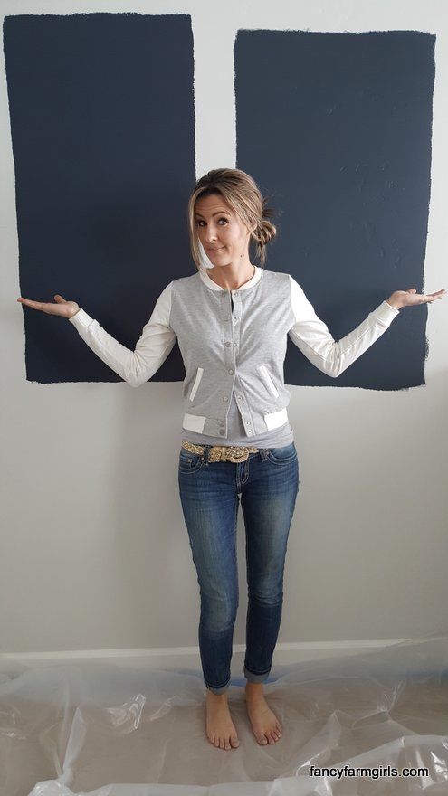 a woman is standing in front of two blue paint squares and holding her hands out