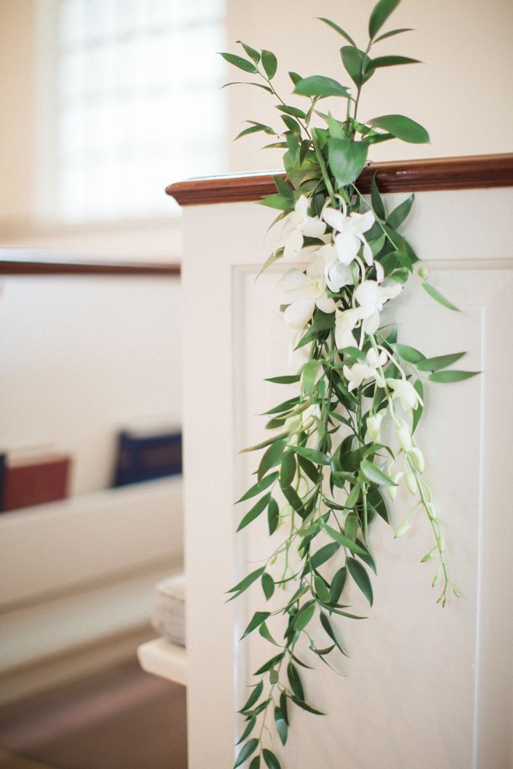 the door is decorated with greenery and white flowers