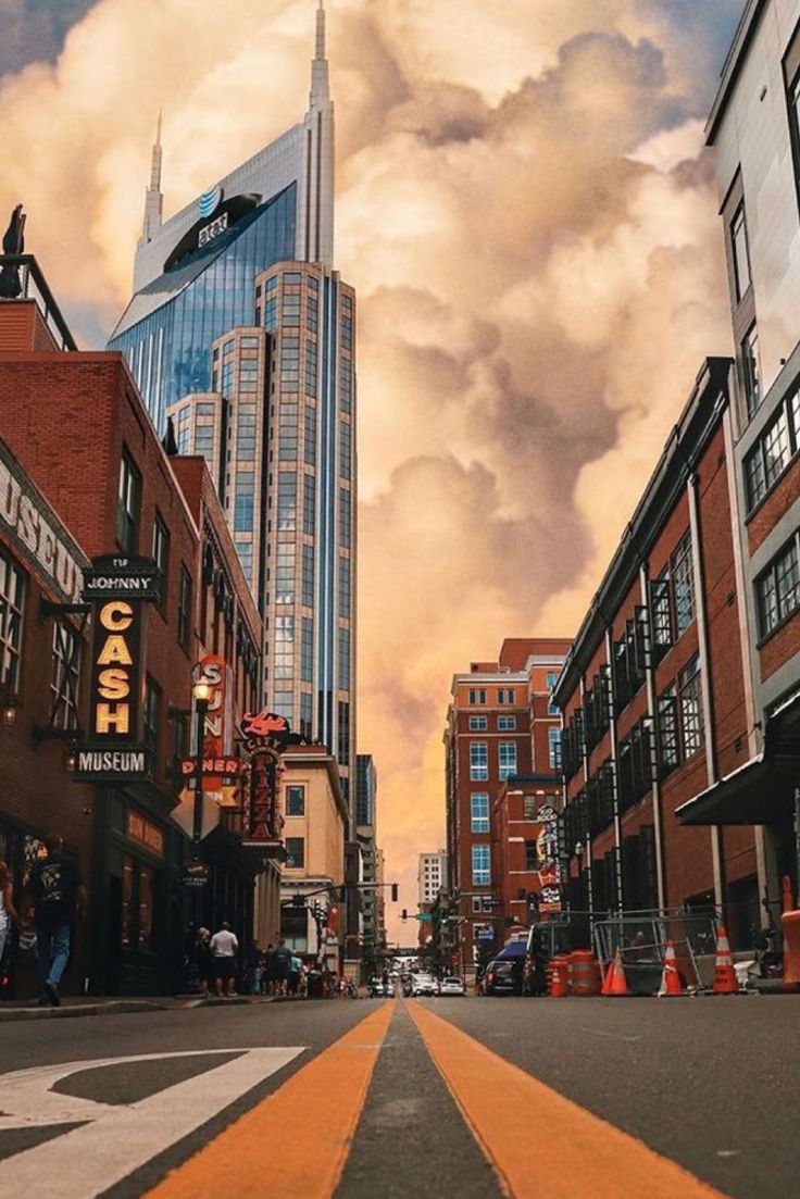 a city street with tall buildings and clouds in the sky over it's head