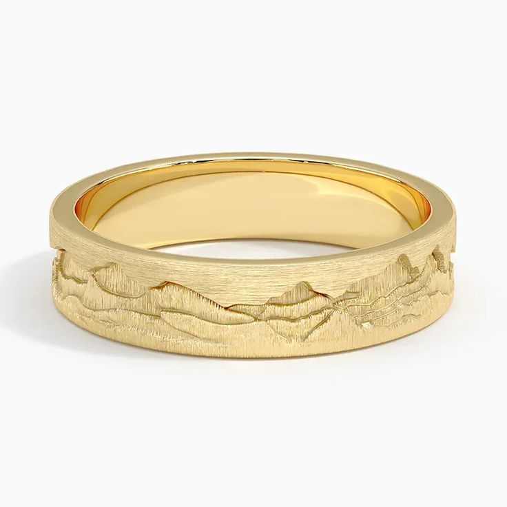 a yellow gold wedding ring with mountains in the middle and waves on it's sides