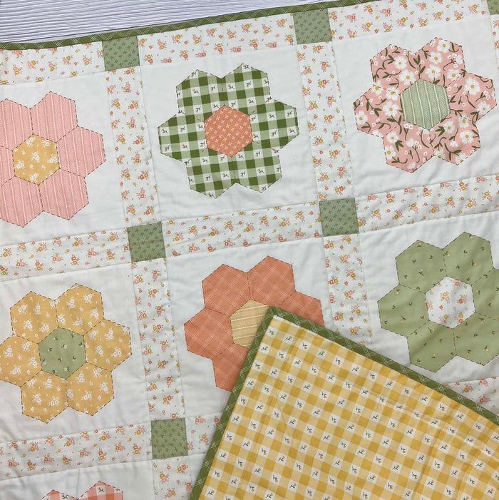 two quilts are laying next to each other on the table top, one has an orange and green patchwork design