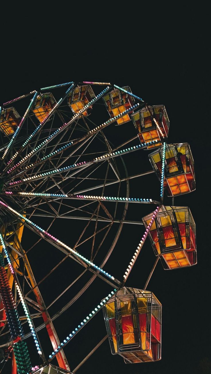 the ferris wheel is brightly lit up at night