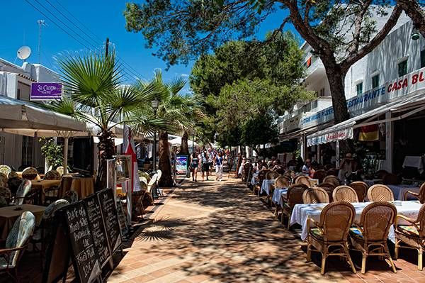 many tables and chairs are set up on the side walk in front of buildings with palm trees