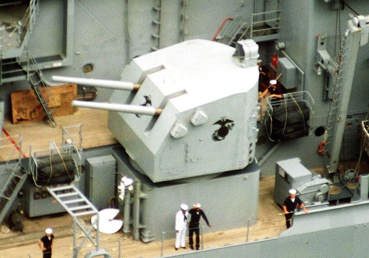 several people standing on the deck of a large ship looking down at an enormous tank