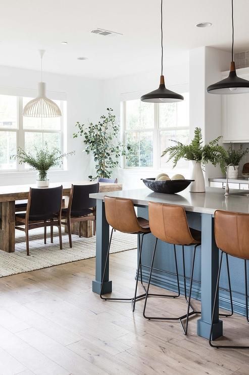 a kitchen island with stools in front of it and potted plants on top