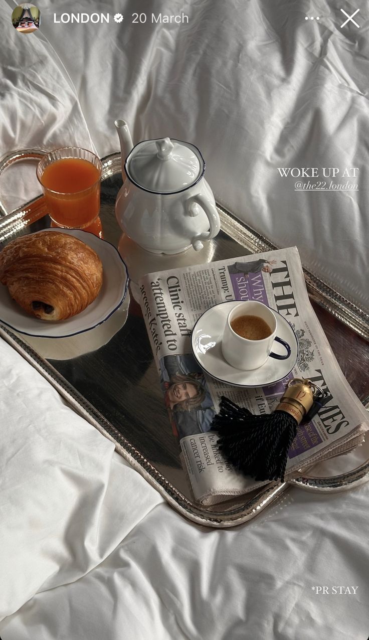 a tray with coffee, croissants and orange juice on it sitting on a bed