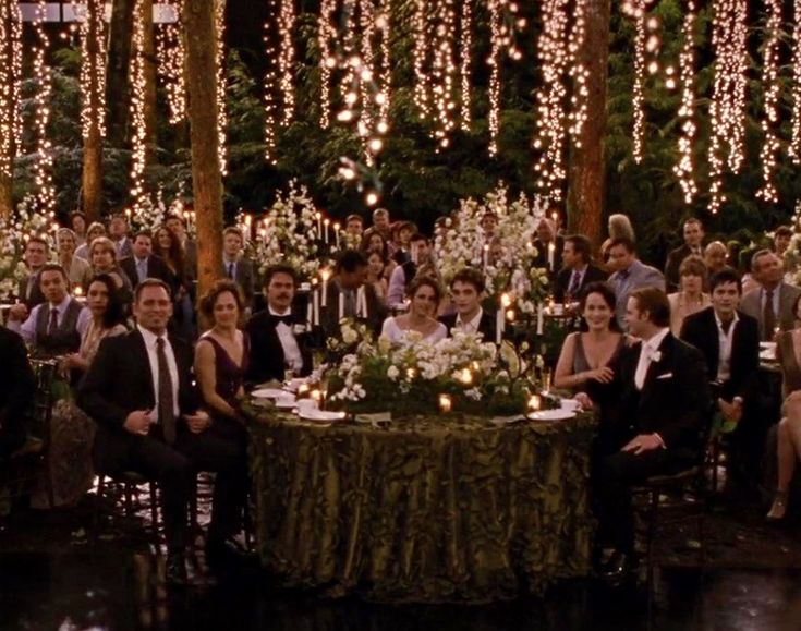 a group of people sitting around a table in front of a wall with lights on it