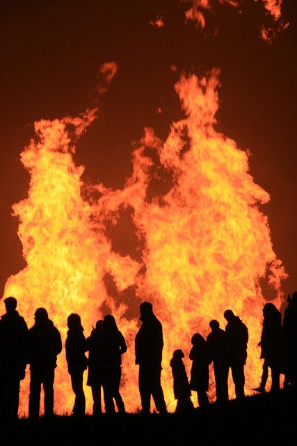 a group of people standing in front of a fire