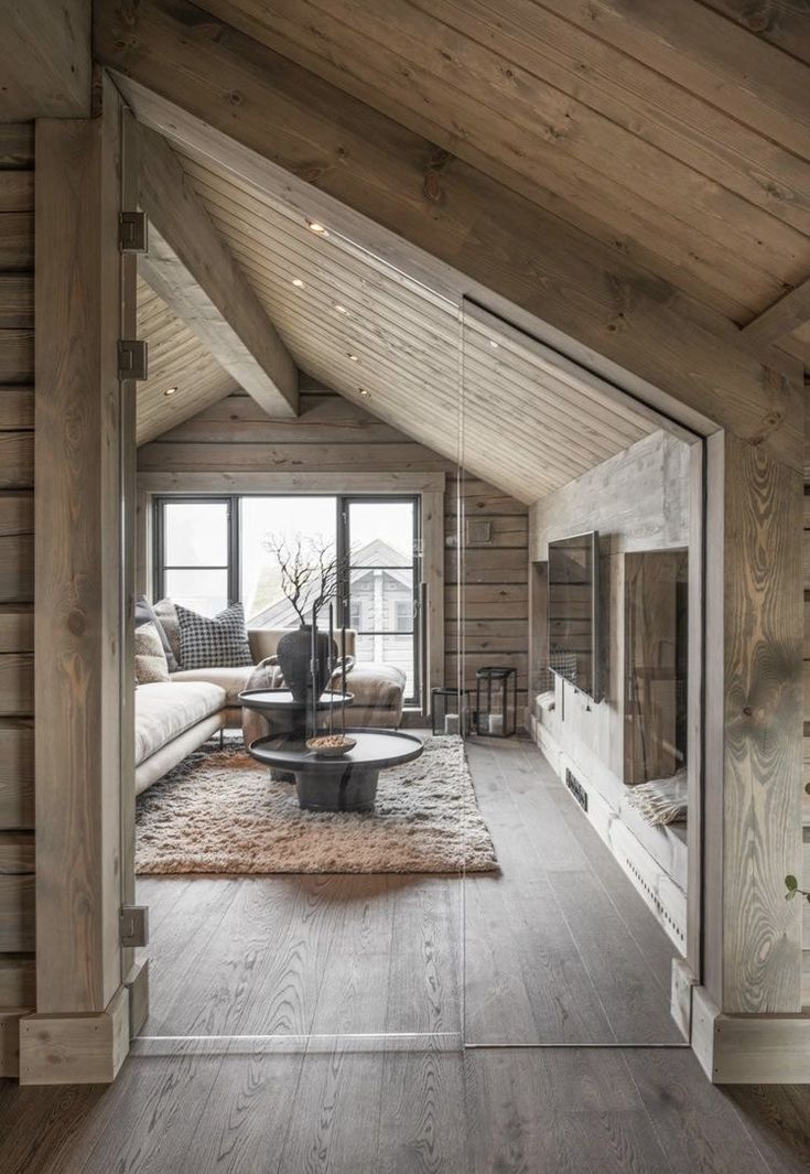 an open living room with wooden walls and flooring is seen from the entry way