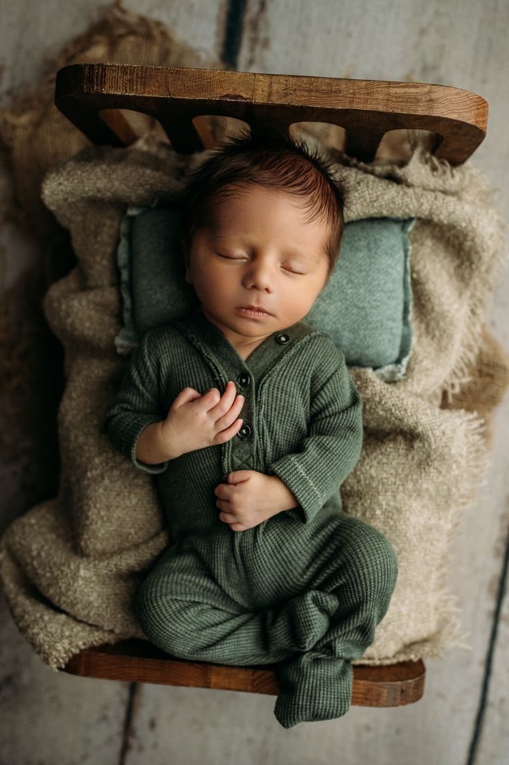 a newborn baby is sleeping in a wooden crate with his hands on his chest and eyes closed