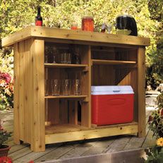 an outdoor bar with cooler and drinks on the outside deck in front of some flowers