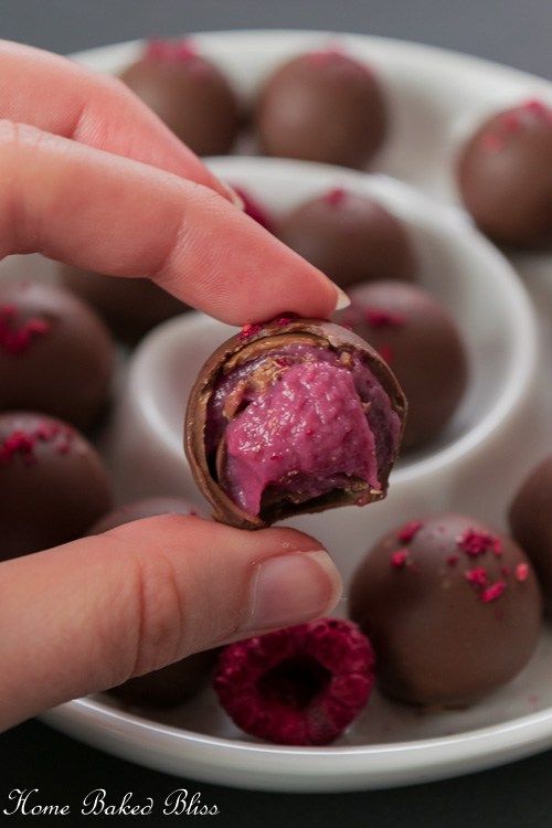 a hand holding a piece of chocolate covered in raspberry