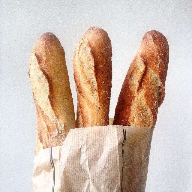 four loaves of bread in a paper bag on a white background with a black stripe