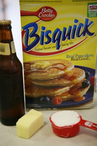 ingredients to make pancakes including butter, sugar and syrup on a counter top with a bottle of bisquick