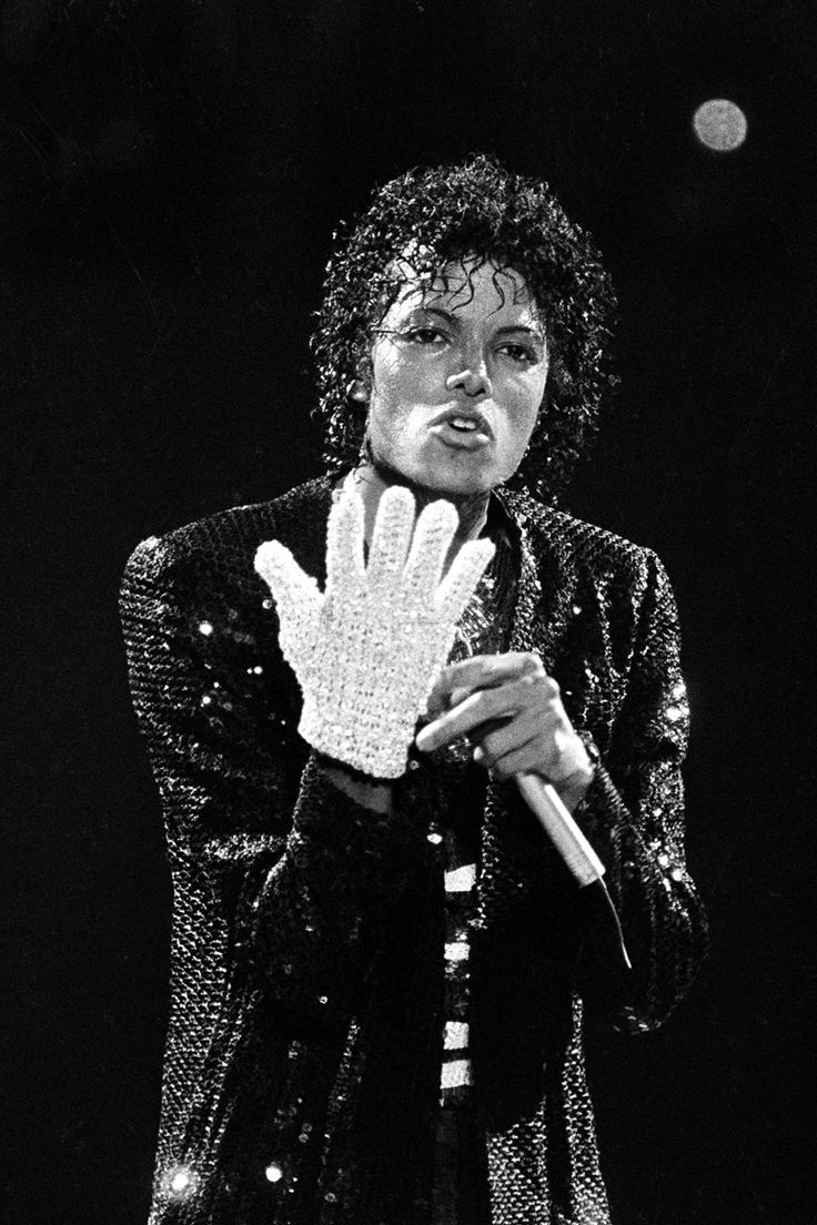 a woman with curly hair holding her hand up in front of her face and looking at the camera