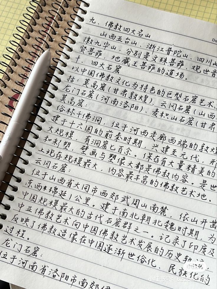 an open notebook with chinese writing on it and a pen resting on the top one