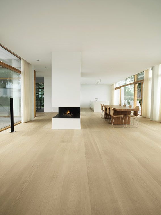 an empty living room with wood floors and white walls, along with large windows that look out onto the outdoors