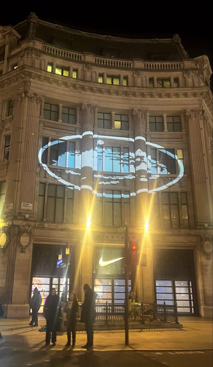 people are standing in front of a building with a batman logo projected on the side