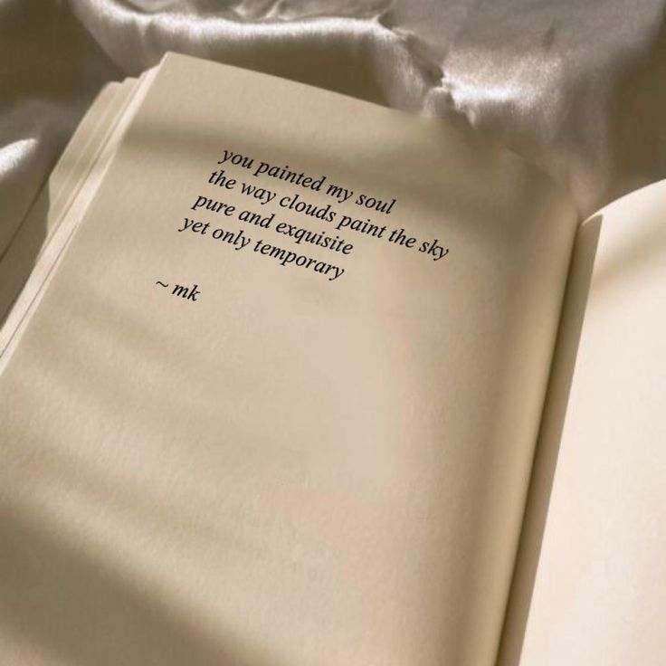 an open book sitting on top of a bed covered in white sheets with a quote