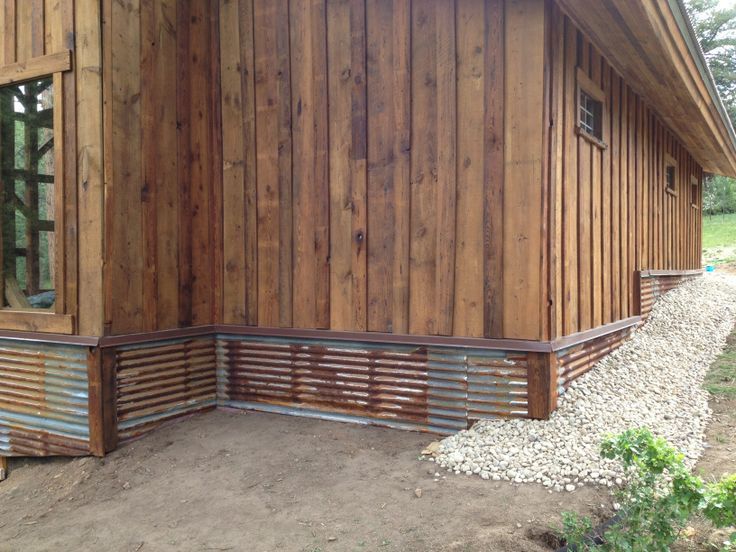 the side of a wooden building with metal slats on it's sides and windows