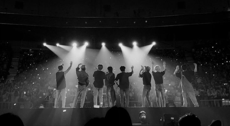 a group of people standing on top of a stage with their hands in the air