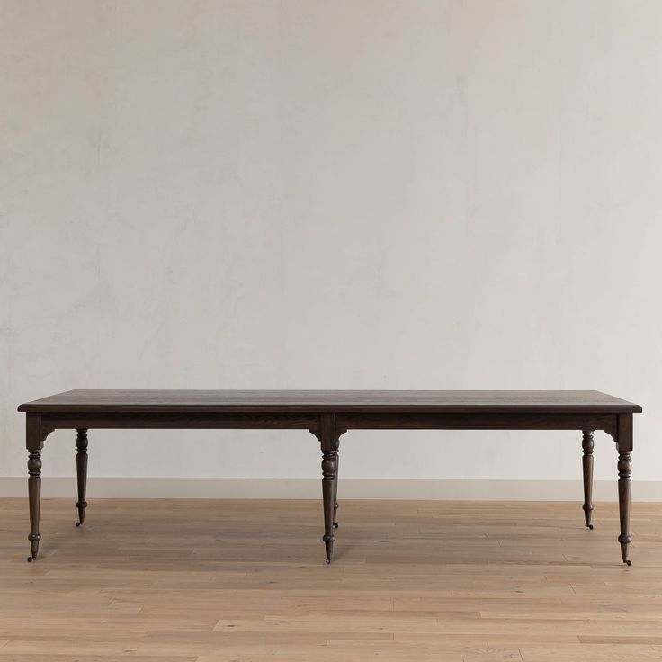 a wooden table sitting on top of a hard wood floor next to a white wall