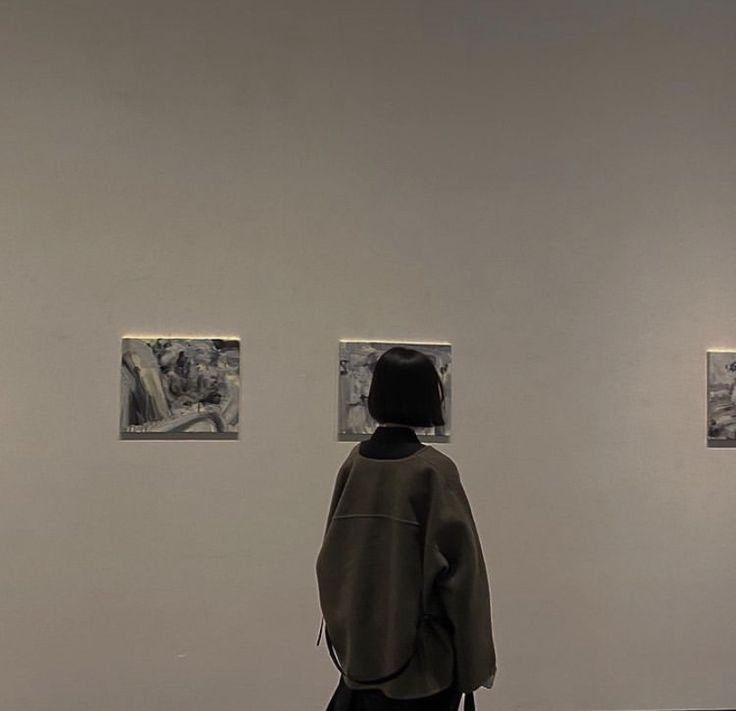 a person standing in front of three pictures on the wall with their back turned to the camera