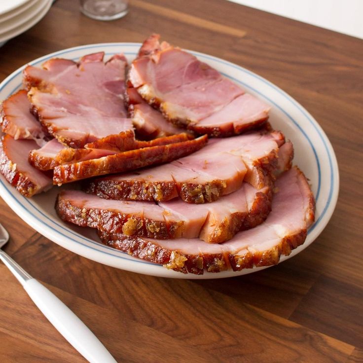 slices of ham on a plate next to silverware