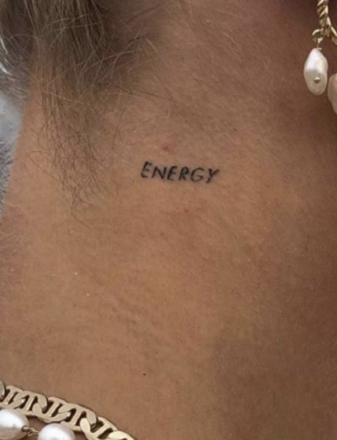 a woman's back neck with the word energy written on it and pearls around her neck