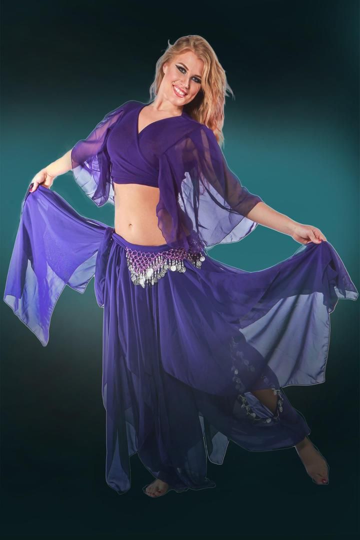 a woman in a purple belly dance outfit posing for the camera with her hands on her hips