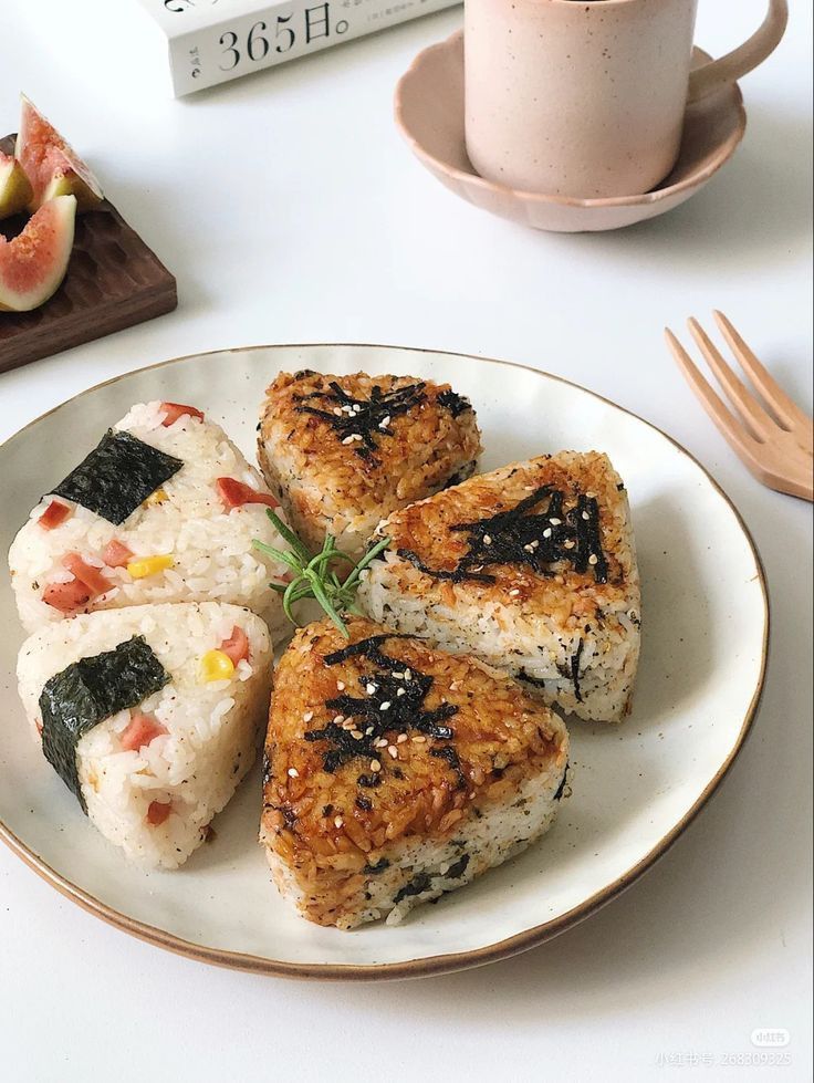 four pieces of sushi on a plate next to a cup of coffee and utensils