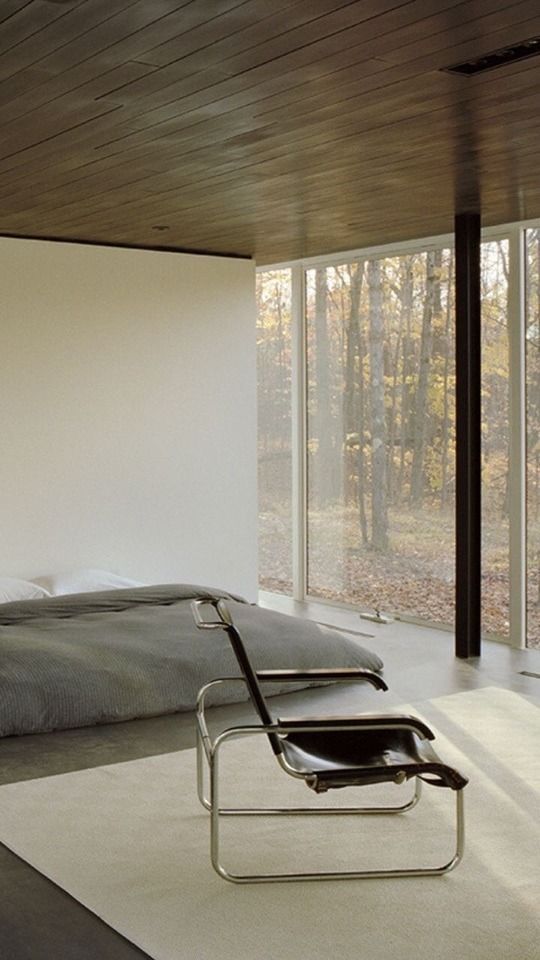 a bedroom with a large bed sitting next to a sliding glass wall that looks out onto the woods