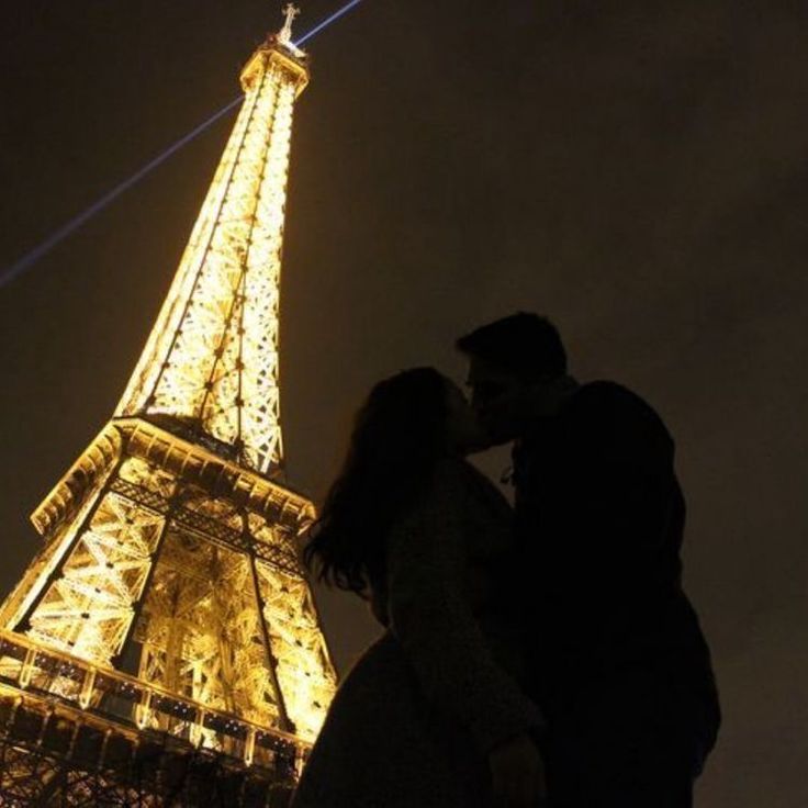 a couple kissing in front of the eiffel tower