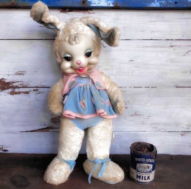 a white stuffed animal with a blue dress next to a can of milk