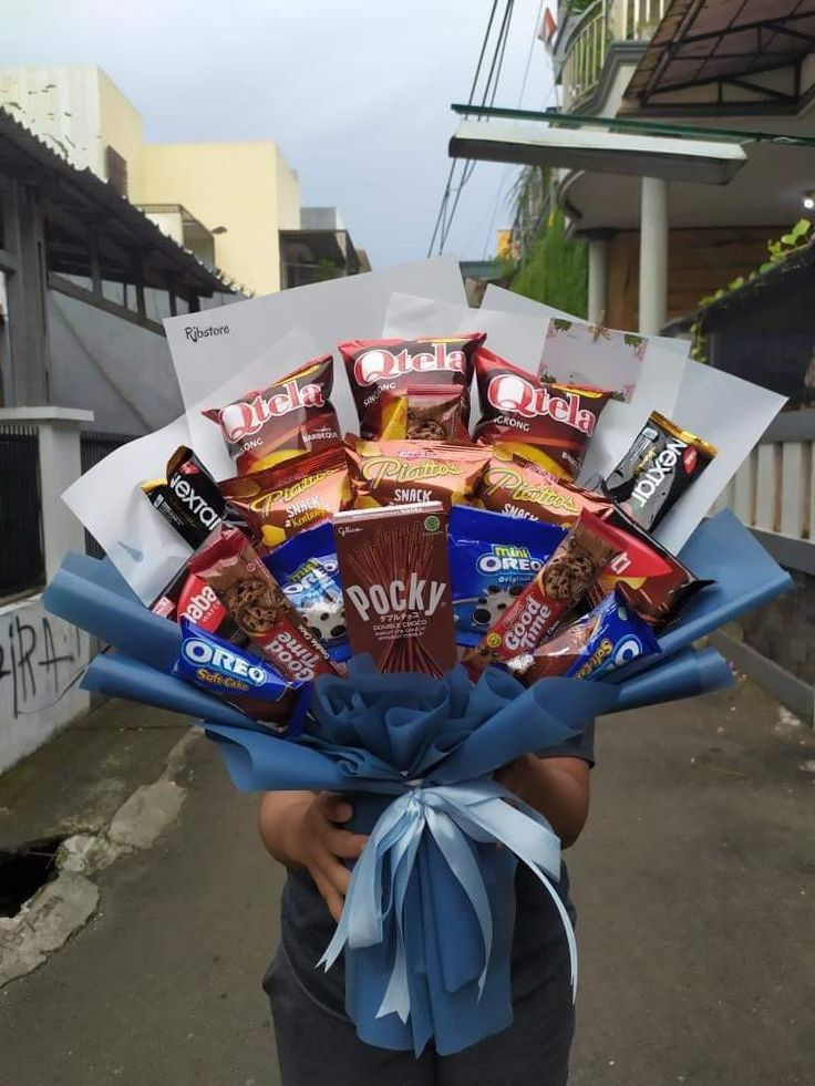 a person holding a bouquet of candy and snacks