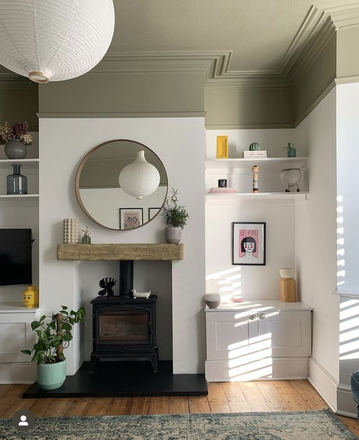 a living room filled with furniture and a fire place under a round mirror on the wall