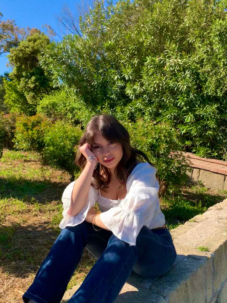 a woman sitting on the edge of a stone wall