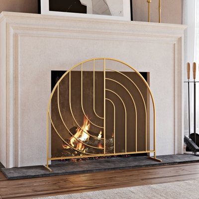 a white fireplace with a gold fire place in front of it and pictures on the wall