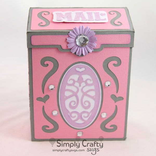 a pink and gray box with an ornate design on the lid, decorated with a flower